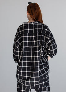 Person wearing a black and white checkered shirt against a gray background