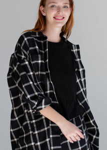Woman wearing a black and white checkered coat over a black top on a gray background