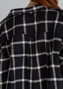 Black and white checkered shirt worn by a person on a gray background