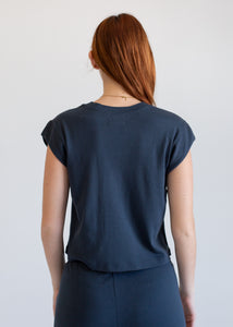 Woman wearing a navy tank and pants against a plain background