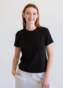 Person wearing a black t-shirt and light gray pants against a white background