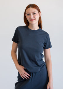 Woman wearing a dark blue t-shirt and pants against a plain background