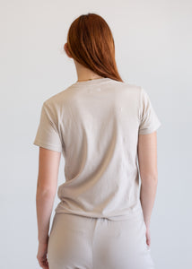 Person wearing a beige t-shirt and pants against a white background