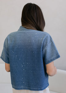 backside of woman wearing cropped indigo short sleeve button down in vintage wash