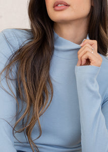 close up of woman wearing long sleeve rib mock neck in sky