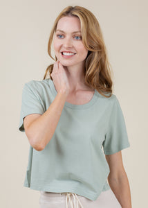 woman wearing cropped tee with open neck in sage
