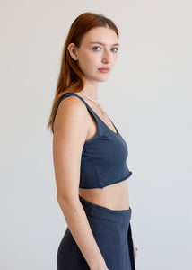 Woman wearing a dark blue athletic top and pants on a light gray background