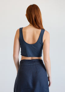 Woman wearing a dark blue sleeveless top and pants on a plain background
