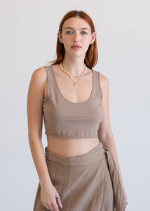 Woman wearing a beige tank top and skirt against a plain background