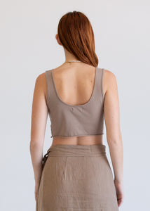 Woman wearing a beige tank top and skirt against a plain background