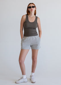Person wearing a dark grey tank top and gray shorts on a white background