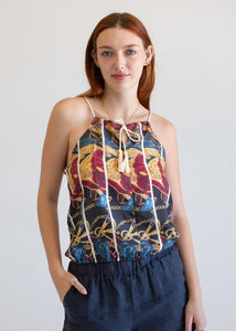 Woman wearing a patterned top with thin straps against a plain background