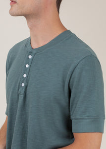 close up of man wearing henley tee in pine green