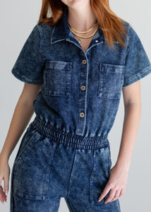 Person wearing a blue denim jumpsuit on a plain background