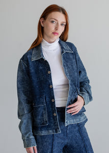 Woman wearing a blue denim jacket and pants on a gray background