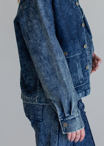 Person wearing a blue denim jacket on a gray background