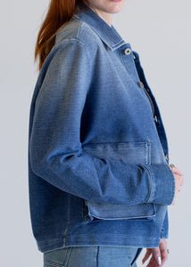 Person wearing a blue denim jacket against a white background