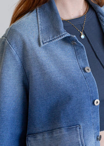 Close-up of a blue denim jacket with a plain background