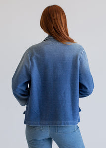 Person wearing a blue denim jacket and jeans on a plain background