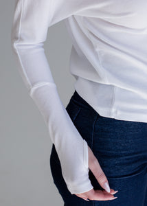 White long-sleeve shirt with sheer sleeves worn by a person on a gray background