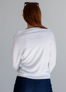 Person wearing a white sweater with a gray background