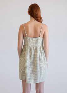 Woman wearing a green checkered dress against a plain background