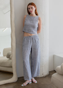 Woman wearing a blue and white checkered outfit in a minimalistic room.