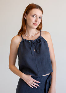 Woman wearing a navy blue halter top with a plain background