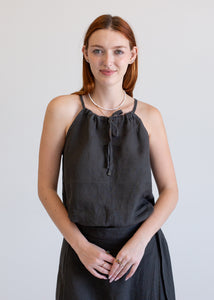 Woman wearing a black sleeveless top and skirt against a plain background