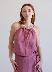 Woman wearing a pink top and skirt set against a plain background