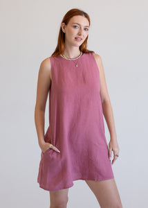 Woman wearing a pink sleeveless dress against a plain background