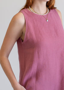 Person wearing a sleeveless pink top with a plain background