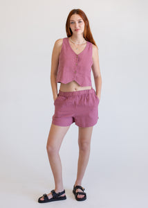 Woman wearing a pink sleeveless top and shorts on a white background