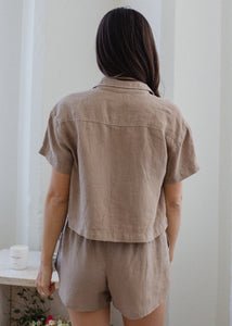back view of woman wearing linen short sleeve shirt in taupe