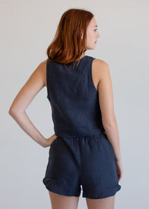 Woman wearing a navy blue sleeveless vest and shorts set against a plain background
