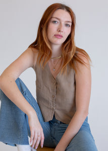 Woman wearing a  mushroom top and blue jeans against a plain background