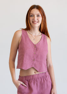 Woman wearing a pink sleeveless vest and shorts on a plain background