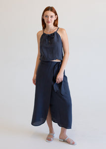 Woman wearing a navy blue tank and skirt with a white background