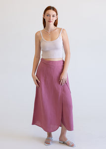 Woman wearing a white tank top and pink skirt on a white background