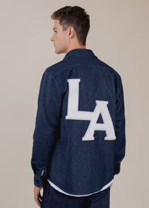 back of man wearing long sleeve indigo button down with LA patch