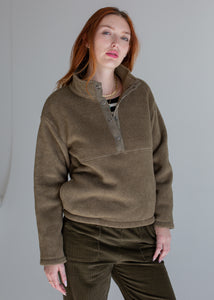 Woman wearing a green fleece pullover with a gray background