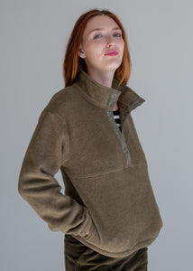 Woman wearing a green fleece pullover against a gray background