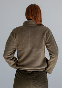 Person wearing a green fleece jacket against a gray background