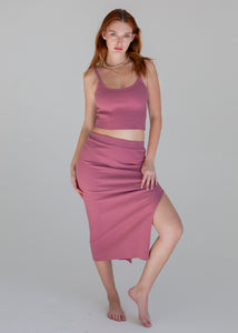 Woman wearing a pink sleeveless top and skirt on a gray background