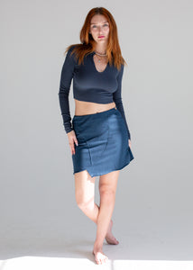 Woman wearing a dark blue long-sleeve top and matching skirt on a gray background
