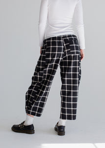 Person wearing black and white plaid pants on a plain background