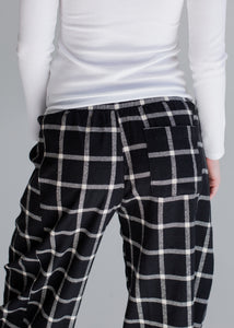 Black and white checkered pants worn by a person on a gray background