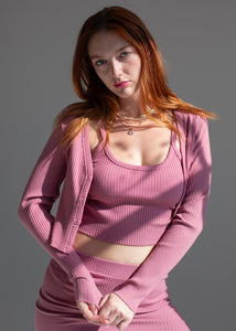 Woman wearing a pink ribbed outfit against a gray background