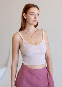 Woman wearing a light pink ribbed tank top and pink pants against a neutral background