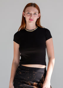 Woman wearing a black crop top against a gray background